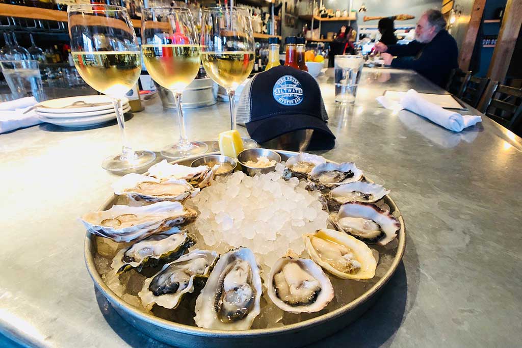 Kick back with fresh oysters and a glass of crisp white wine at Saltwater Fish House & Oyster Bar. Credit: Scott Meis